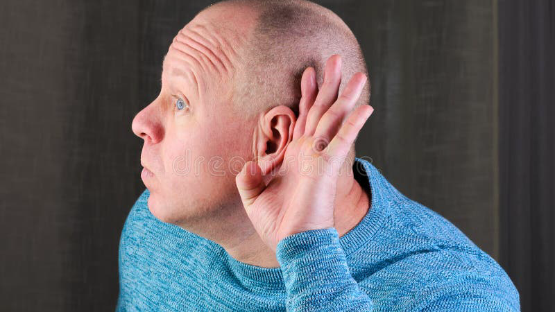 person with hand cupped to ear, looking concerned